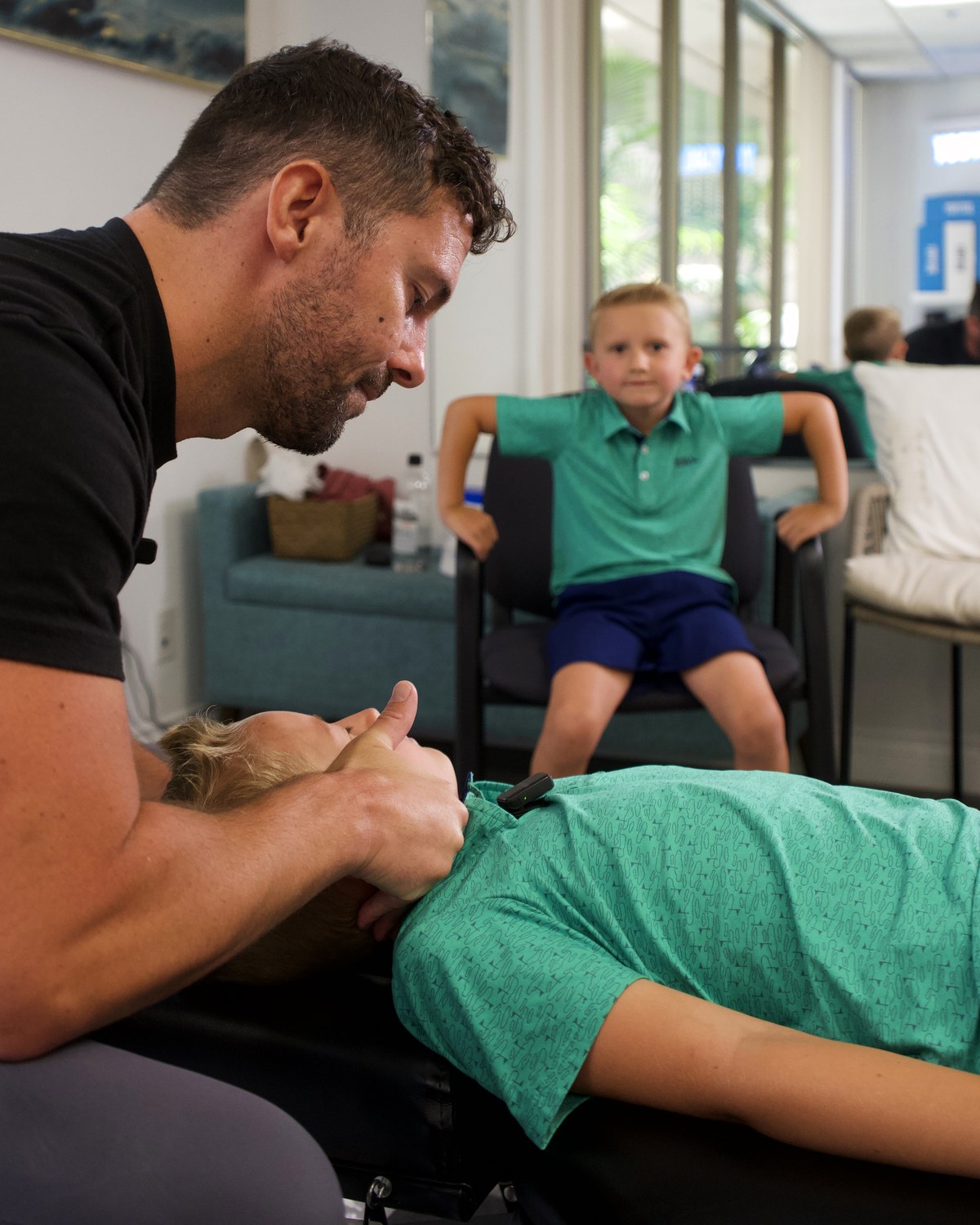 Dr. Alex adjusting a young patient while his brother watches
